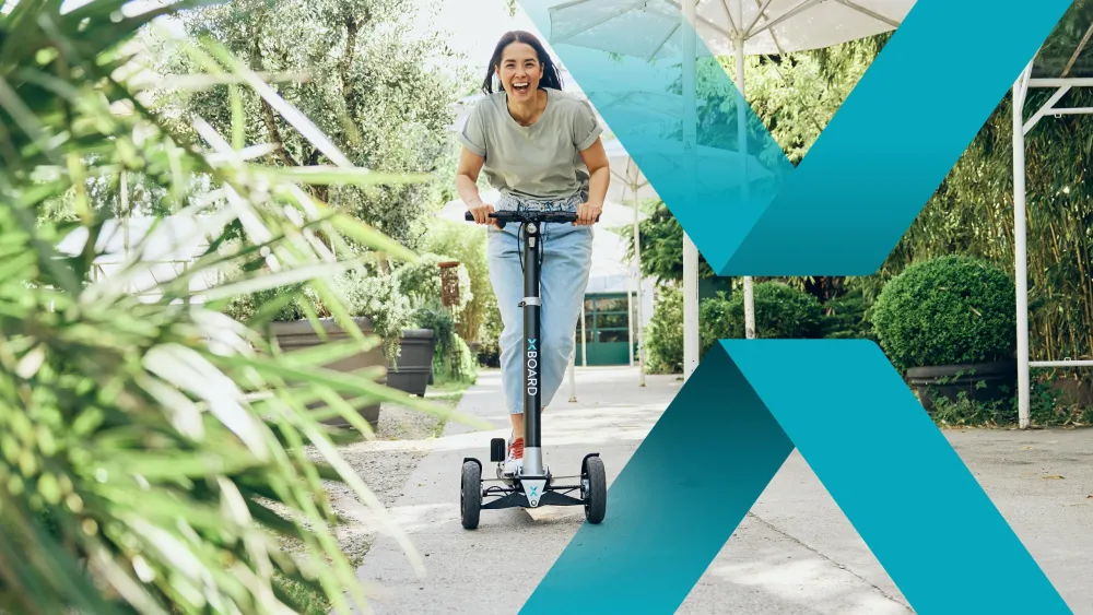 Frau fährt lächelnd auf einem E-Scooter durch eine grüne Gartenumgebung.