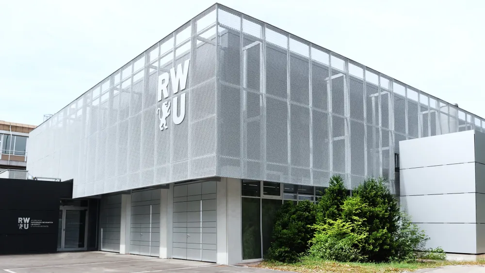 Modernes Gebäude mit perforierter Metallfassade und Grünfläche