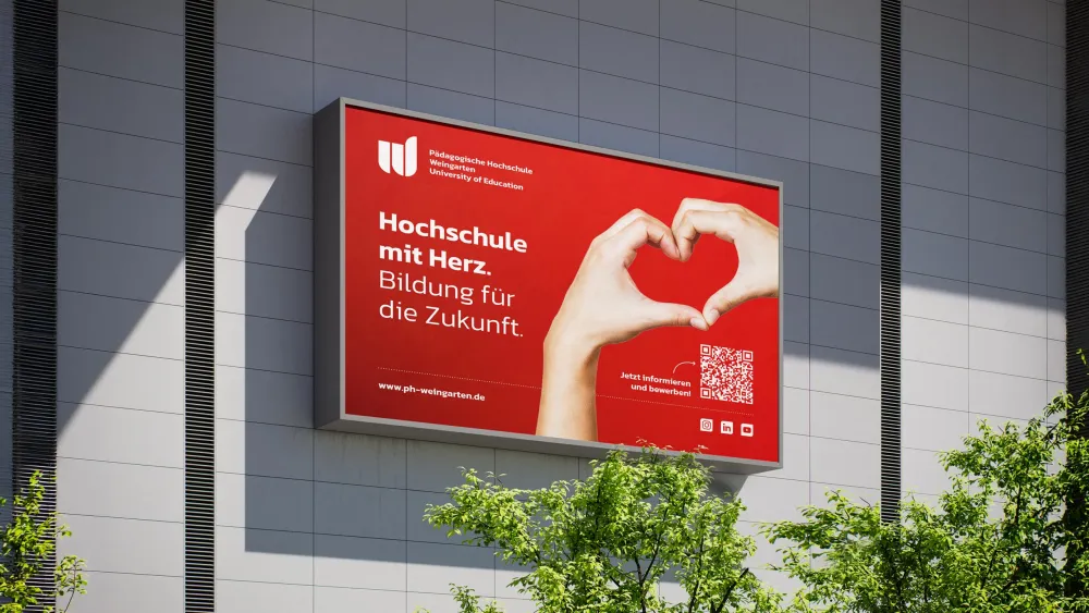 Rote Werbetafel mit Herzsymbol an grauer Gebäudefassade