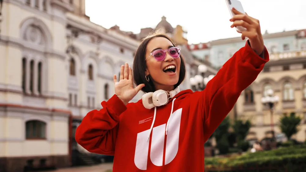 Junge Frau in rotem Hoodie macht ein Selfie in der Stadt