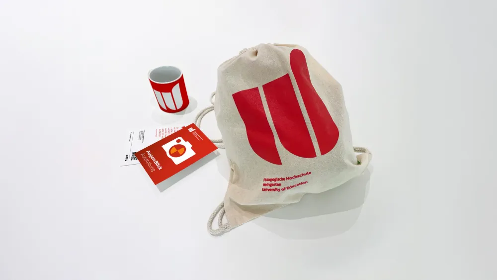 Merchandise der Pädagogischen Hochschule Weingarten: Beutel, Tasse und Flyer mit Logo.