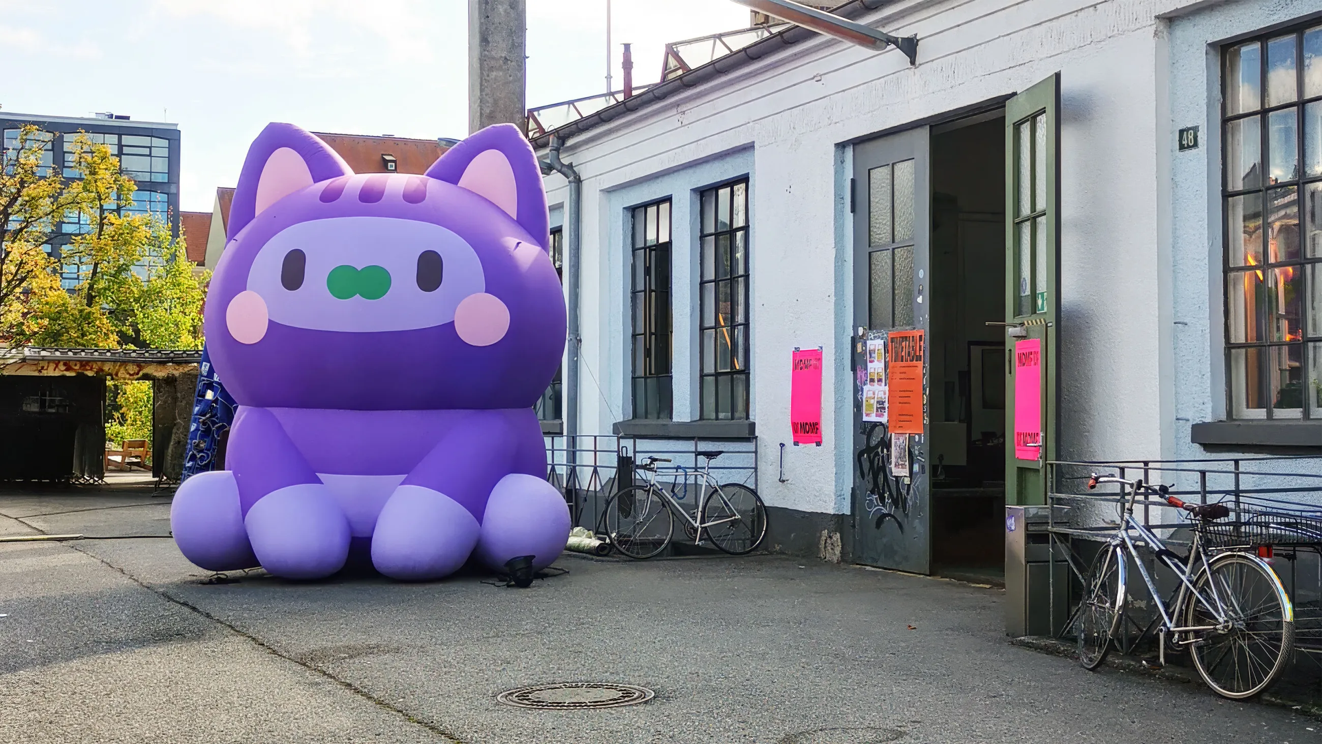 Große violette aufblasbare Katzen-Skulptur vor Veranstaltungsgebäude